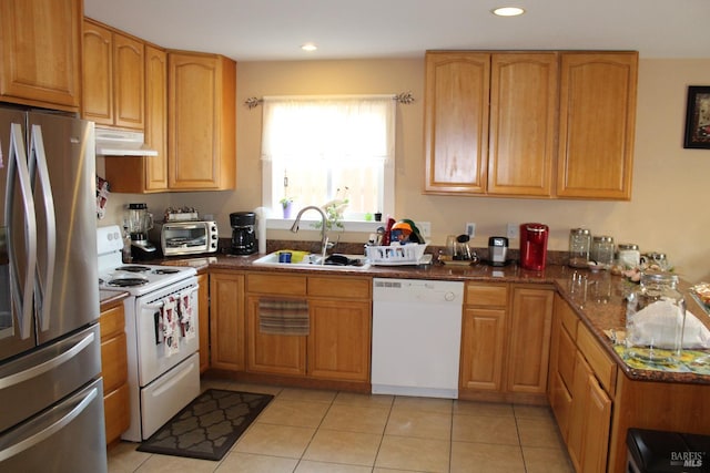 kitchen with light tile patterned floors, sink, white appliances, and dark stone counters