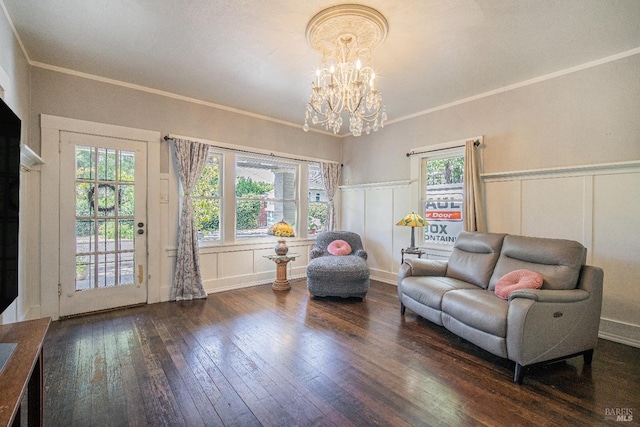 living room with dark hardwood / wood-style flooring, crown molding, and an inviting chandelier