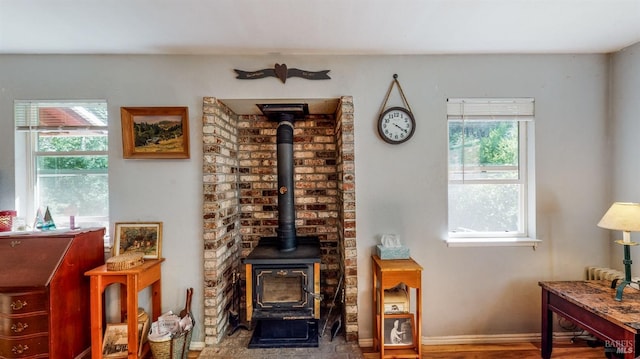 interior space featuring a wood stove, hardwood / wood-style flooring, plenty of natural light, and brick wall