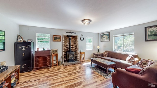 living room featuring a wood stove, light wood-type flooring, and plenty of natural light