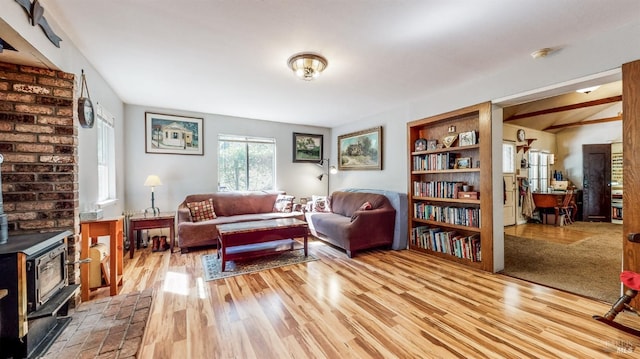 living area featuring light wood-type flooring, brick wall, and a wood stove