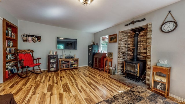 living room with a wood stove, hardwood / wood-style flooring, and brick wall