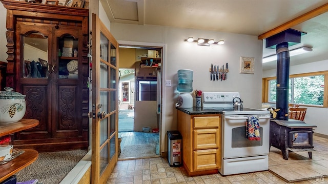 kitchen featuring dark countertops, a wood stove, and white electric stove