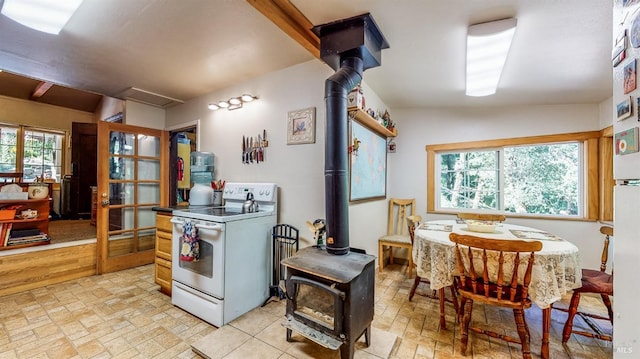 kitchen featuring a wood stove, white electric range, light tile patterned floors, and a healthy amount of sunlight