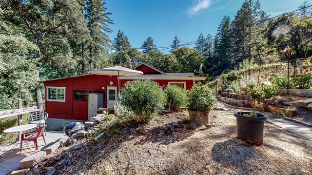 back of property featuring a patio area and a vegetable garden
