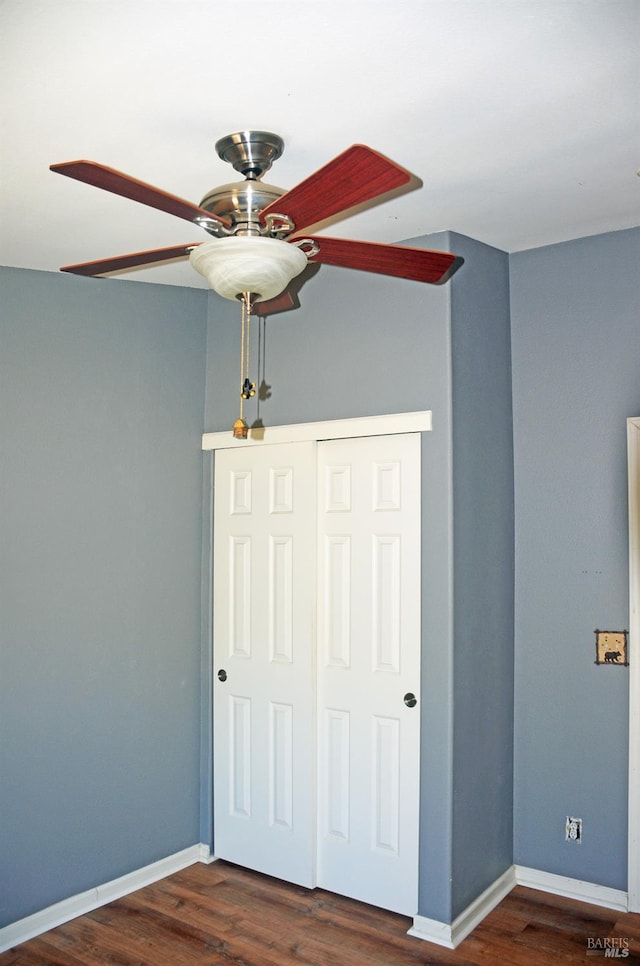 unfurnished bedroom featuring ceiling fan, dark hardwood / wood-style floors, and a closet