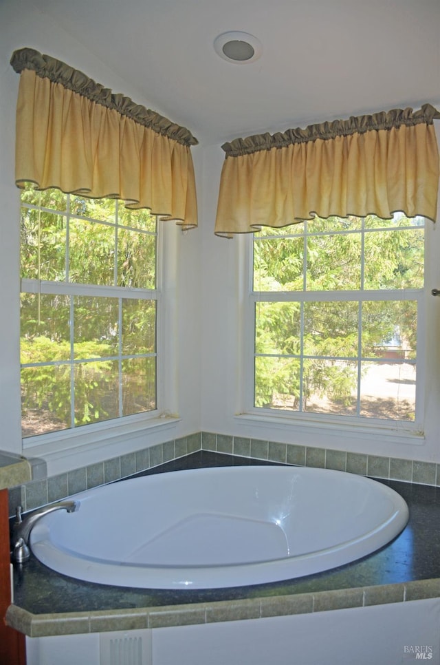 bathroom with tiled tub and plenty of natural light