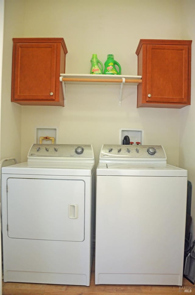 laundry room featuring independent washer and dryer, light hardwood / wood-style flooring, and cabinets