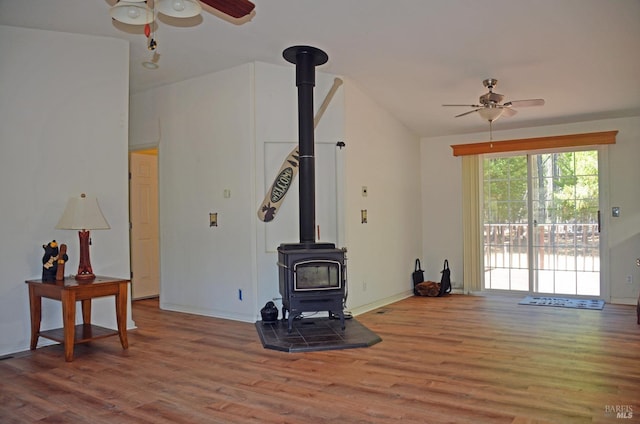 living room featuring ceiling fan, wood-type flooring, and a wood stove