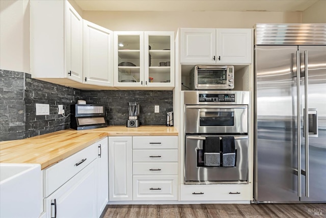 kitchen with stainless steel appliances, white cabinets, and butcher block counters