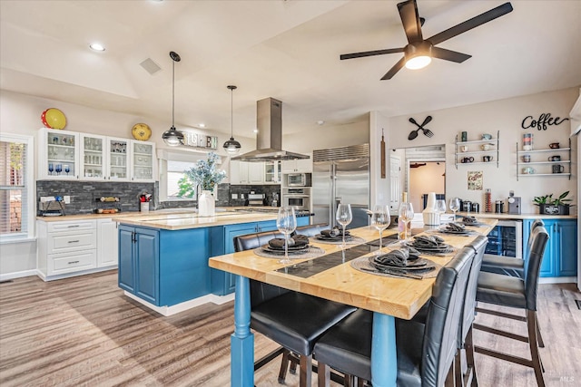 kitchen featuring island exhaust hood, a kitchen island, built in appliances, and a wealth of natural light