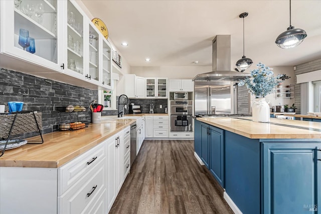 kitchen featuring pendant lighting, wood counters, white cabinetry, island range hood, and blue cabinetry