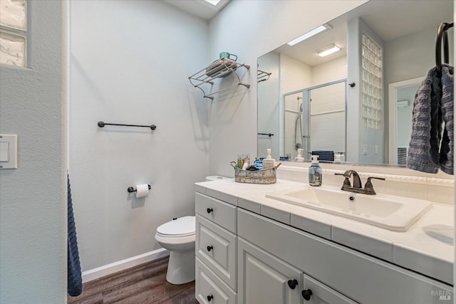 bathroom featuring wood-type flooring, vanity, toilet, and a shower with door