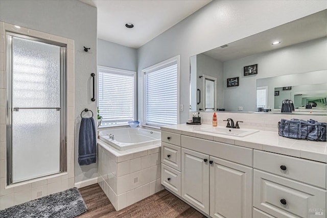 bathroom with independent shower and bath, hardwood / wood-style flooring, and vanity