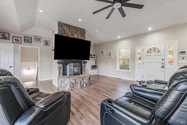 living room featuring a stone fireplace, vaulted ceiling, hardwood / wood-style floors, and ceiling fan