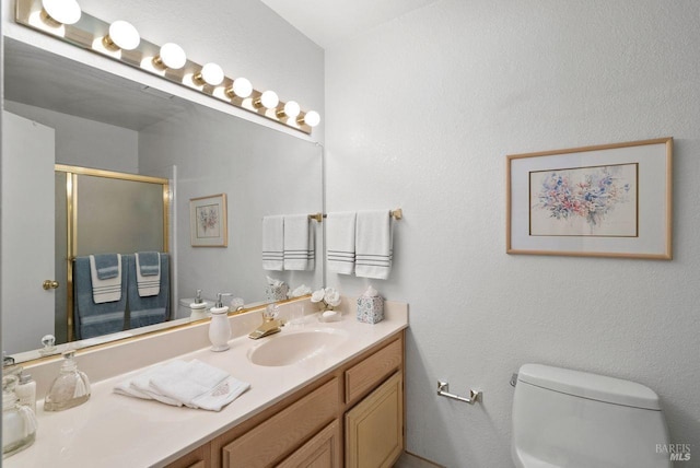 bathroom with vanity, toilet, and a shower with shower door