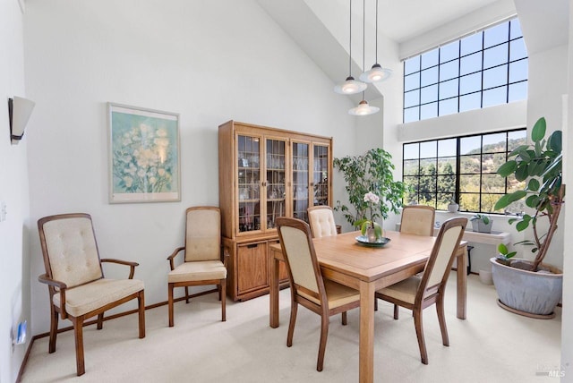 dining area with light carpet and high vaulted ceiling