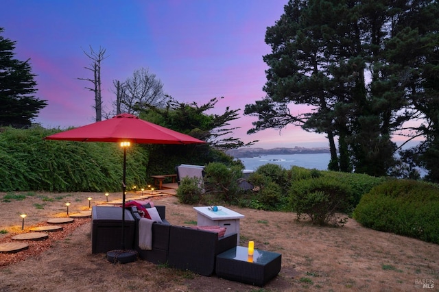 patio terrace at dusk featuring a water view and an outdoor hangout area