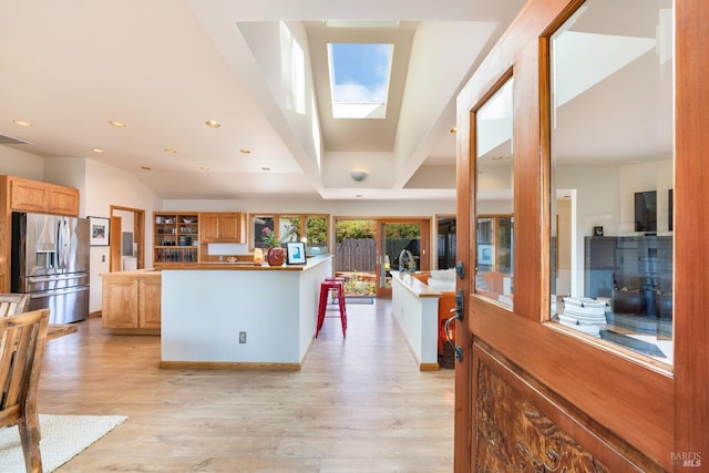 kitchen with a kitchen island, stainless steel fridge, light hardwood / wood-style floors, and a skylight