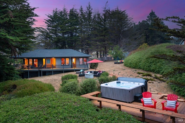 back house at dusk featuring a wooden deck, an outdoor living space, and a hot tub