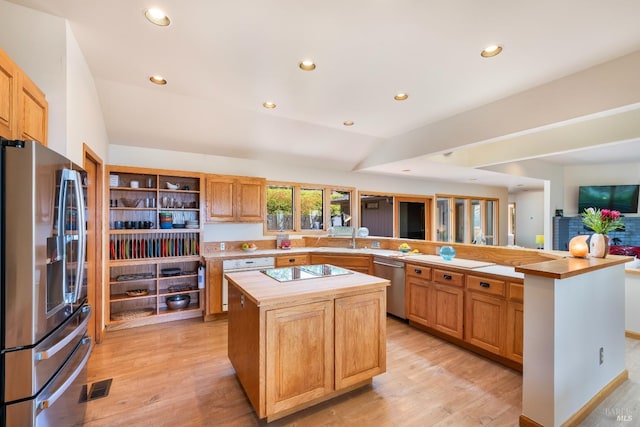 kitchen featuring stainless steel appliances, kitchen peninsula, a kitchen island, and light wood-type flooring