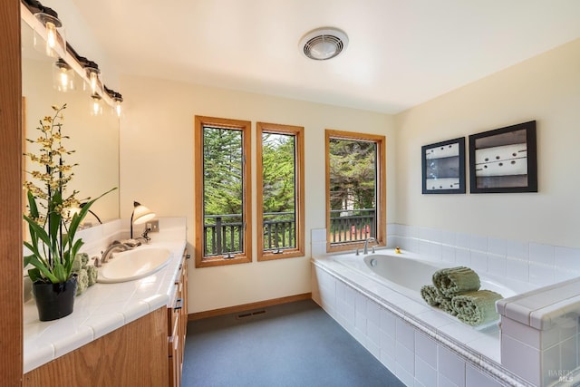 bathroom featuring a relaxing tiled tub and vanity