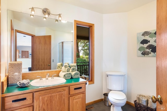 bathroom with vanity, a shower with door, and toilet