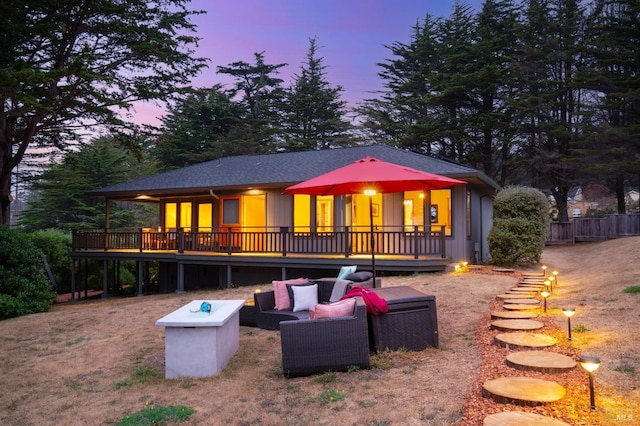 back house at dusk featuring an outdoor hangout area and a deck