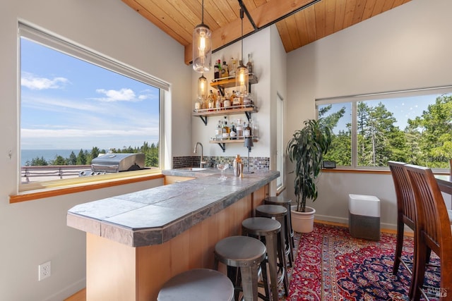 bar featuring baseboards, a sink, wooden ceiling, and wet bar