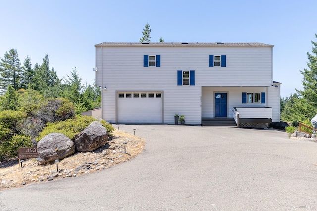 art deco inspired home featuring a garage and aphalt driveway