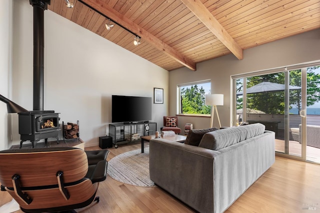 living room featuring light wood-type flooring, wooden ceiling, a wood stove, rail lighting, and beamed ceiling