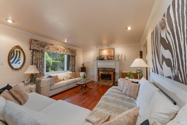 living room featuring crown molding, wood-type flooring, and a tiled fireplace