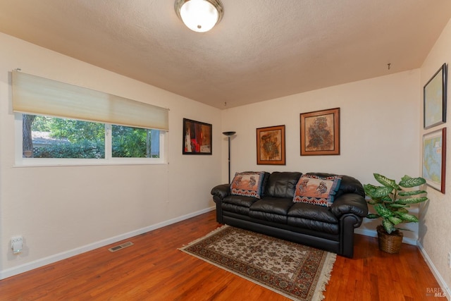 living room with wood-type flooring and a textured ceiling