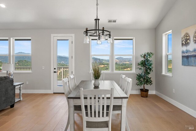 dining space featuring a notable chandelier, a mountain view, light wood-type flooring, and lofted ceiling