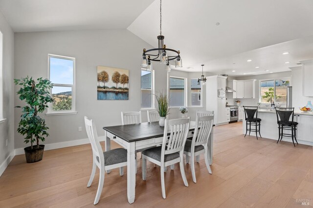 dining space featuring light wood-type flooring, an inviting chandelier, and vaulted ceiling