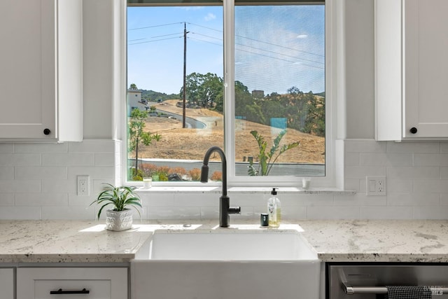 kitchen with tasteful backsplash, light stone counters, sink, and white cabinets