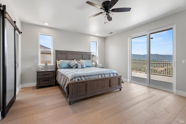 bedroom with a mountain view, light hardwood / wood-style flooring, and ceiling fan