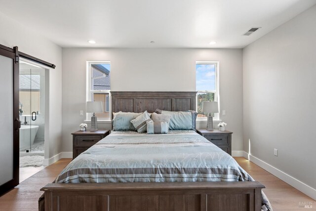 bedroom featuring a barn door and light hardwood / wood-style floors