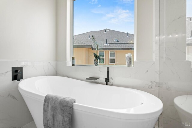 bathroom featuring a bathtub and tile walls