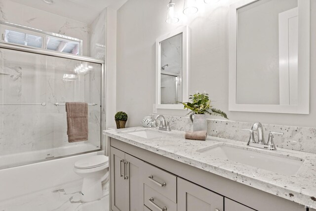 full bathroom featuring vanity, bath / shower combo with glass door, and toilet