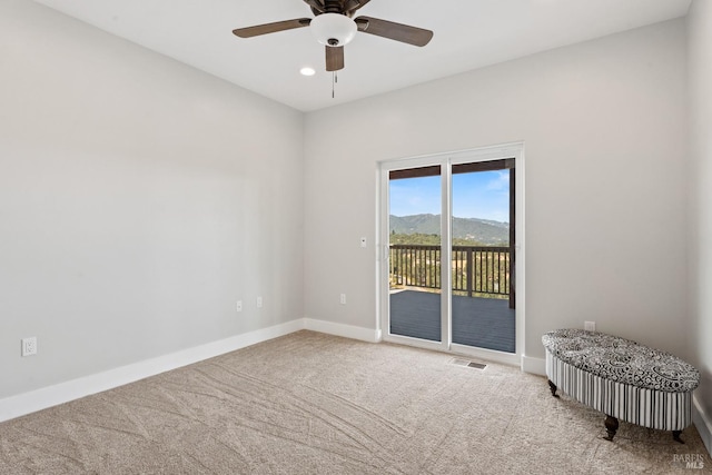 empty room featuring a mountain view, carpet, and ceiling fan