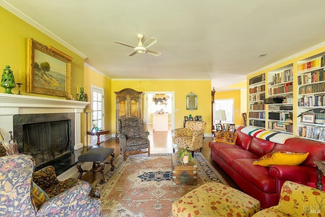 living room with ceiling fan, a premium fireplace, ornamental molding, and wood-type flooring