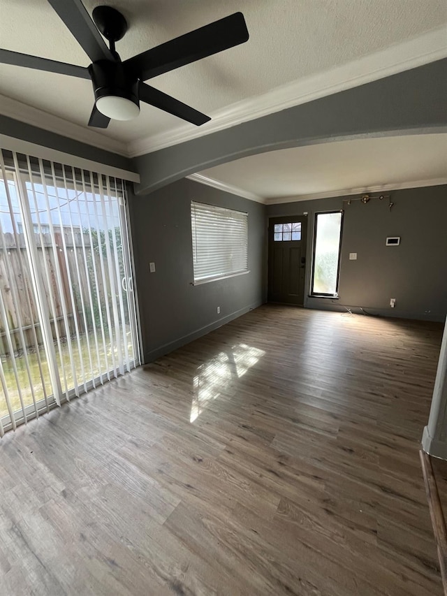 interior space with ceiling fan, a textured ceiling, crown molding, and wood finished floors