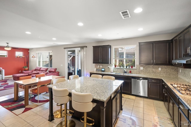 kitchen featuring dishwasher, a center island, gas stovetop, ceiling fan, and decorative backsplash