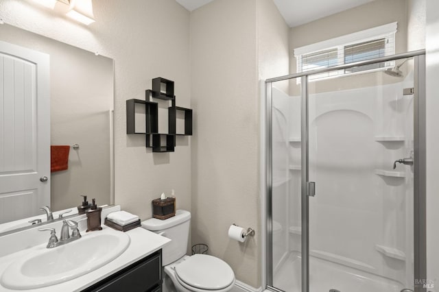 bathroom featuring a shower with door, vanity, and toilet