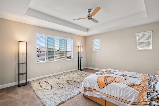 carpeted bedroom featuring ceiling fan and a raised ceiling