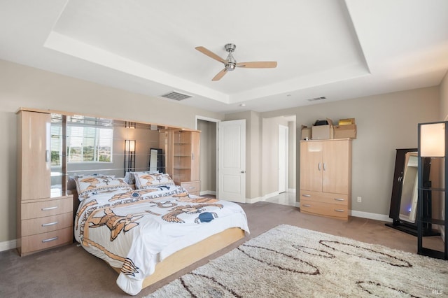 carpeted bedroom with ceiling fan and a raised ceiling