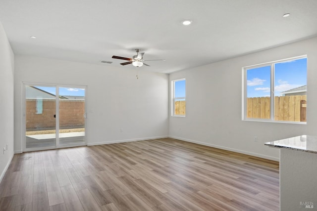 empty room with ceiling fan and light hardwood / wood-style floors