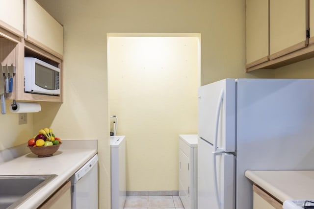 kitchen with cream cabinets, light tile patterned flooring, white appliances, and washer / dryer