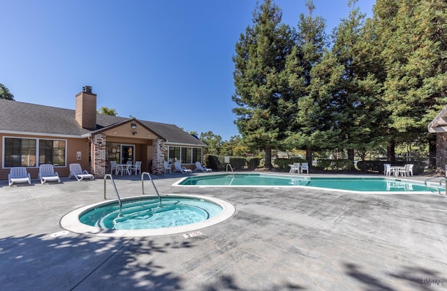 view of swimming pool featuring a patio area and a hot tub